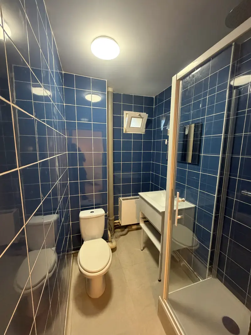 Salle de douche rénovée avec carrelage bleu nuit par Angus Travaux