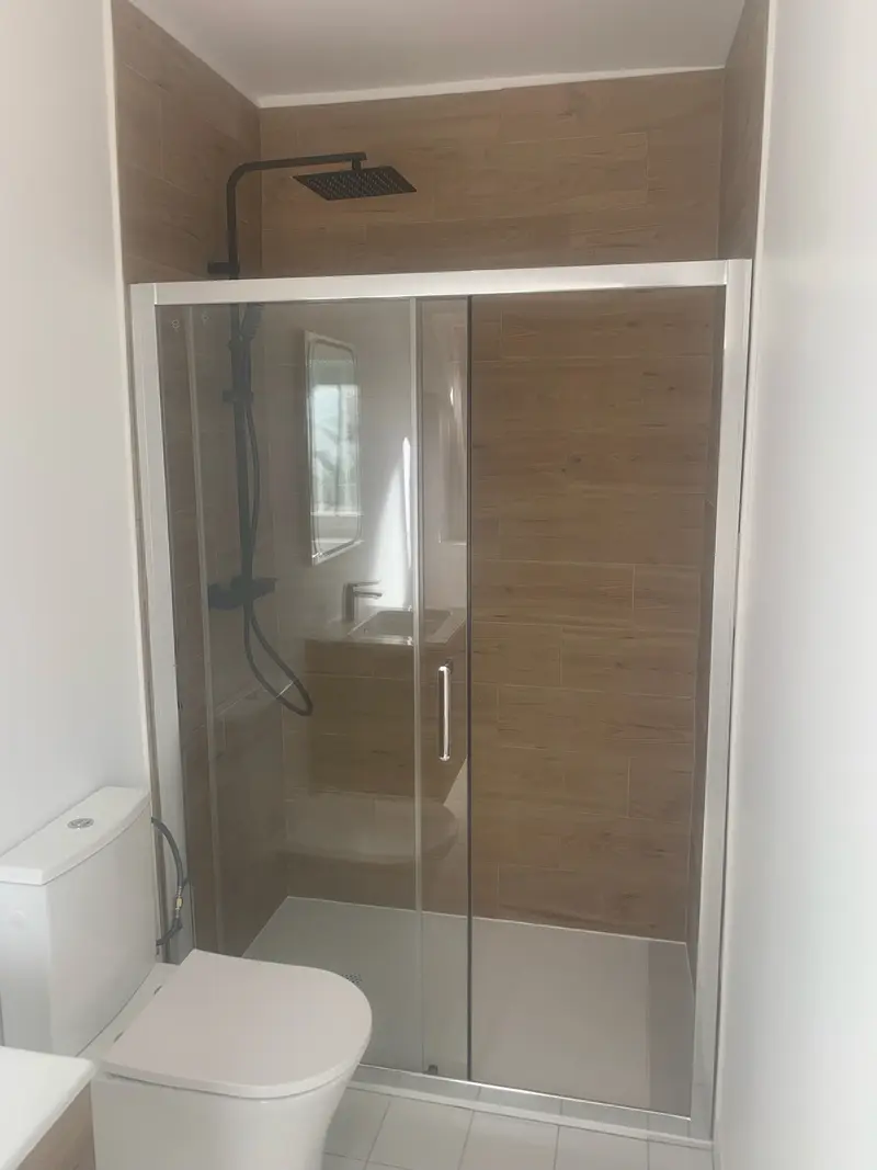 Salle de douche après rénovation : douche vitrée et carrelage effet bois